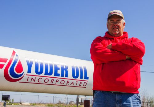 Yoder Oil sales representative standing in front of a propane tank wearing a red shirt