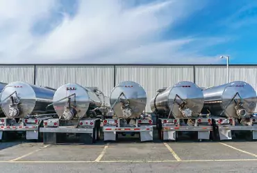 A row of five gasoline trucks sitting in front of a building for gasoline delivery in McLean County IL.