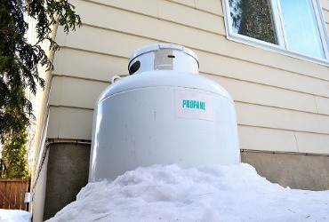 white propane tank sitting next to house in the snow